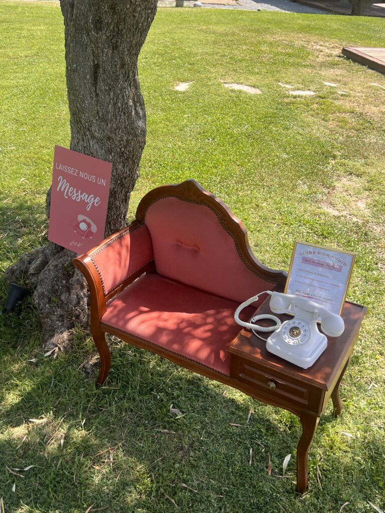 Espace livre d’or audio avec téléphone vintage blanc sur banc ancien, idée originale pour un mariage champêtre – L’effet Maria wedding planner