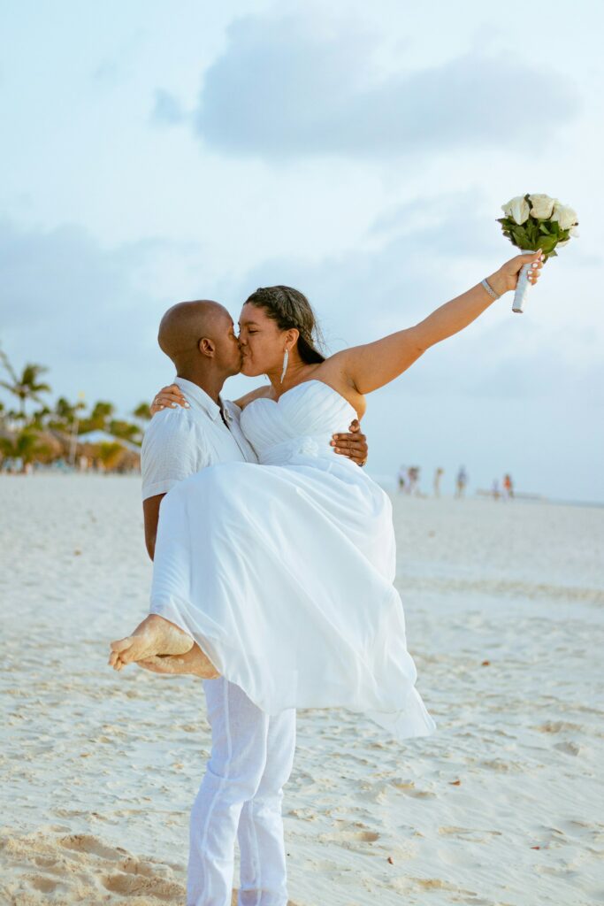 Couple de mariés sautant de joie en bord de mer, célébration d’un mariage joyeux et décontracté – L’effet Maria wedding planner