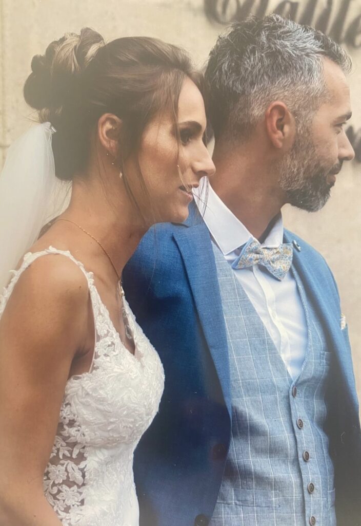 Portrait élégant d’un couple de mariés, elle en robe en dentelle blanche, lui en costume bleu avec nœud papillon – mariage chic organisé par L’effet Maria