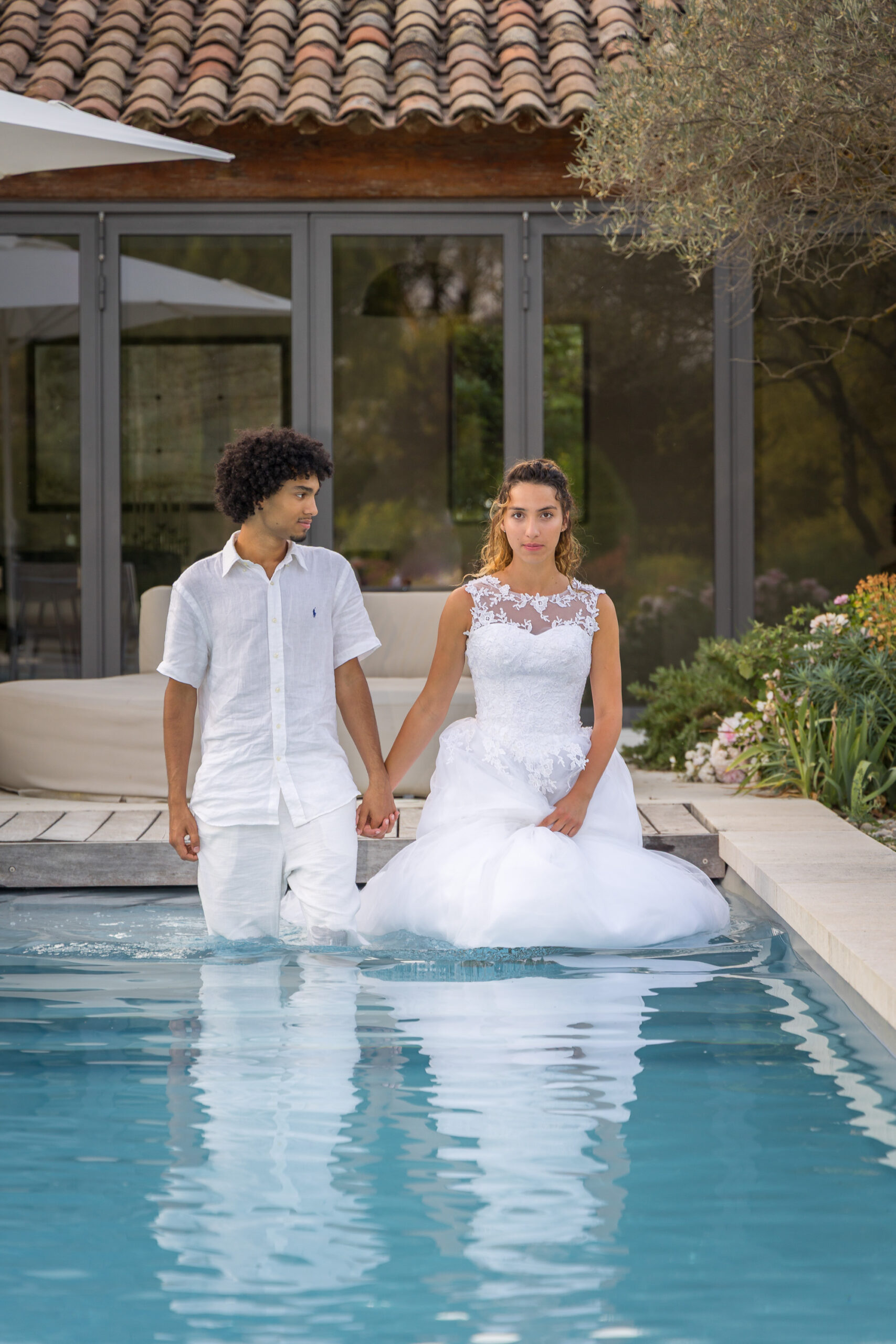 Couple de mariés dans une piscine, main dans la main – photo originale et audacieuse d’un mariage organisé par L’effet Maria