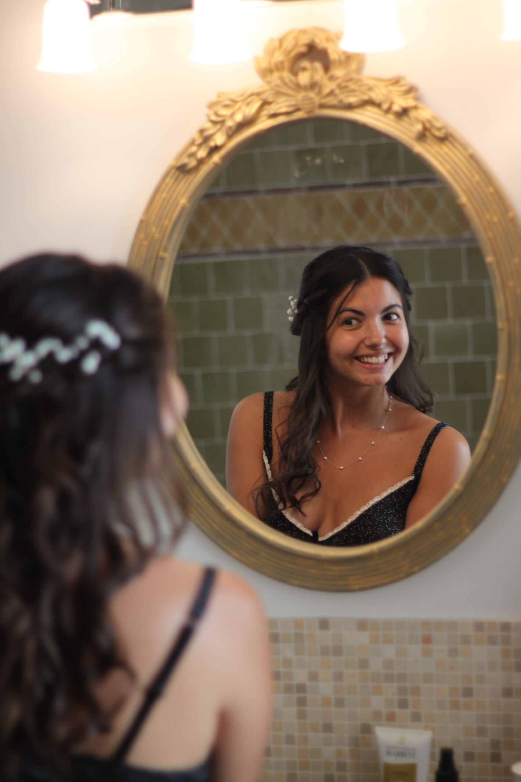 Mariée souriante se regardant dans un miroir doré au style rétro.