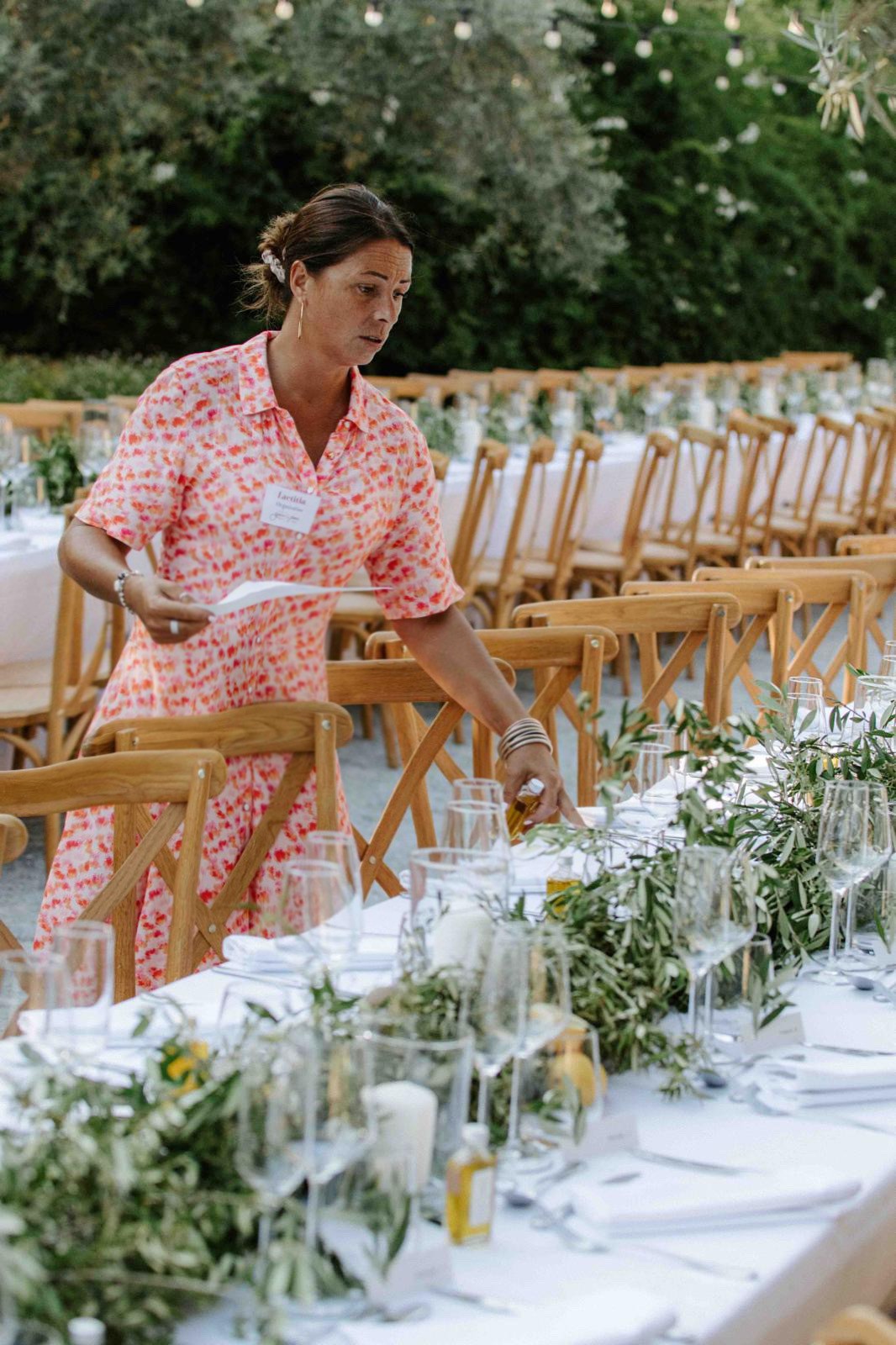 Wedding planner installant des bougies sur une table de réception décorée de branches d’olivier – L’effet Maria en pleine préparation de mariage alt="wedding planner en Provence